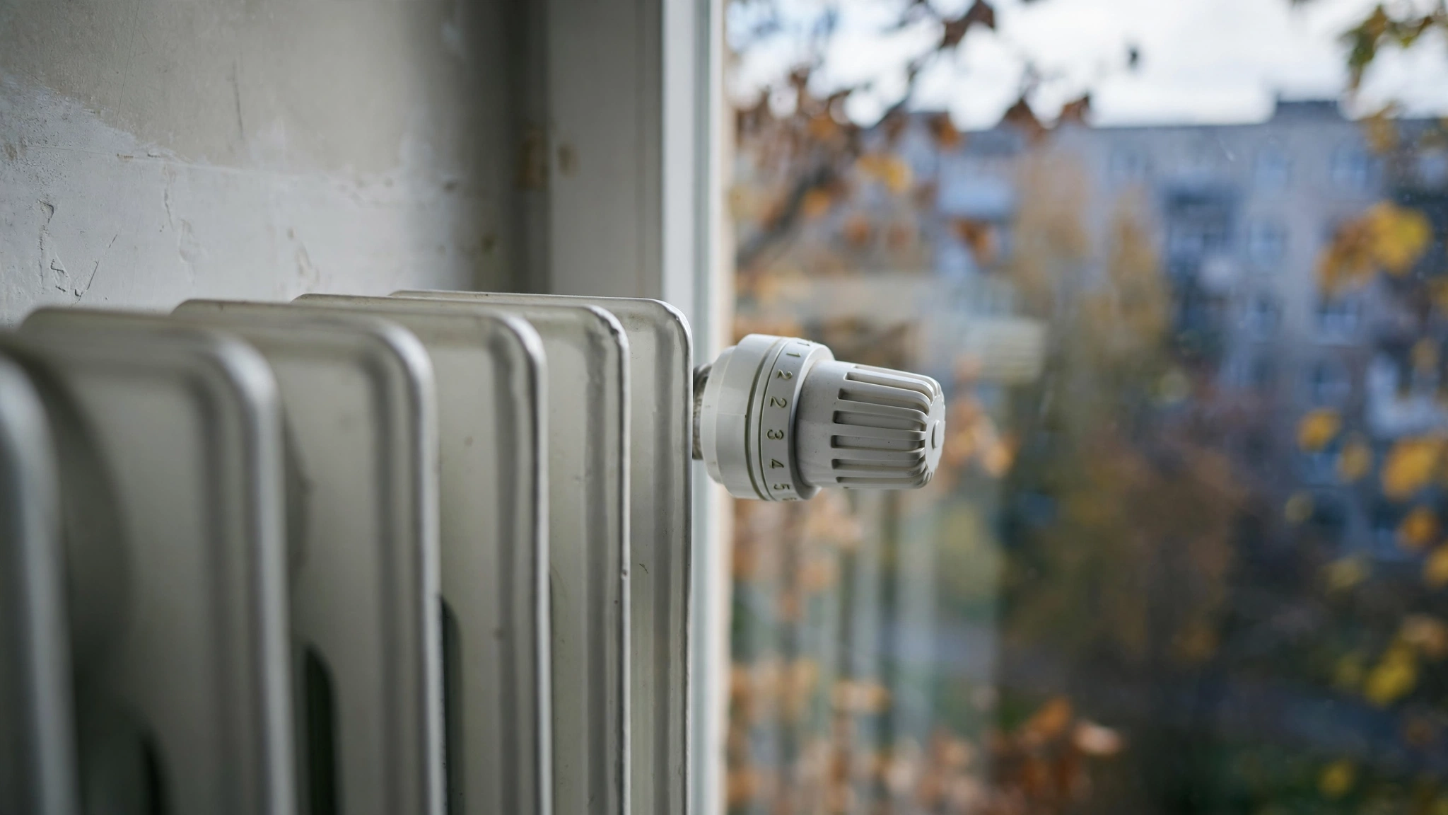 Blok mieszkalny w Olsztynie jesienią, zbliżenie na kaloryfer z głowicą termostatyczną
